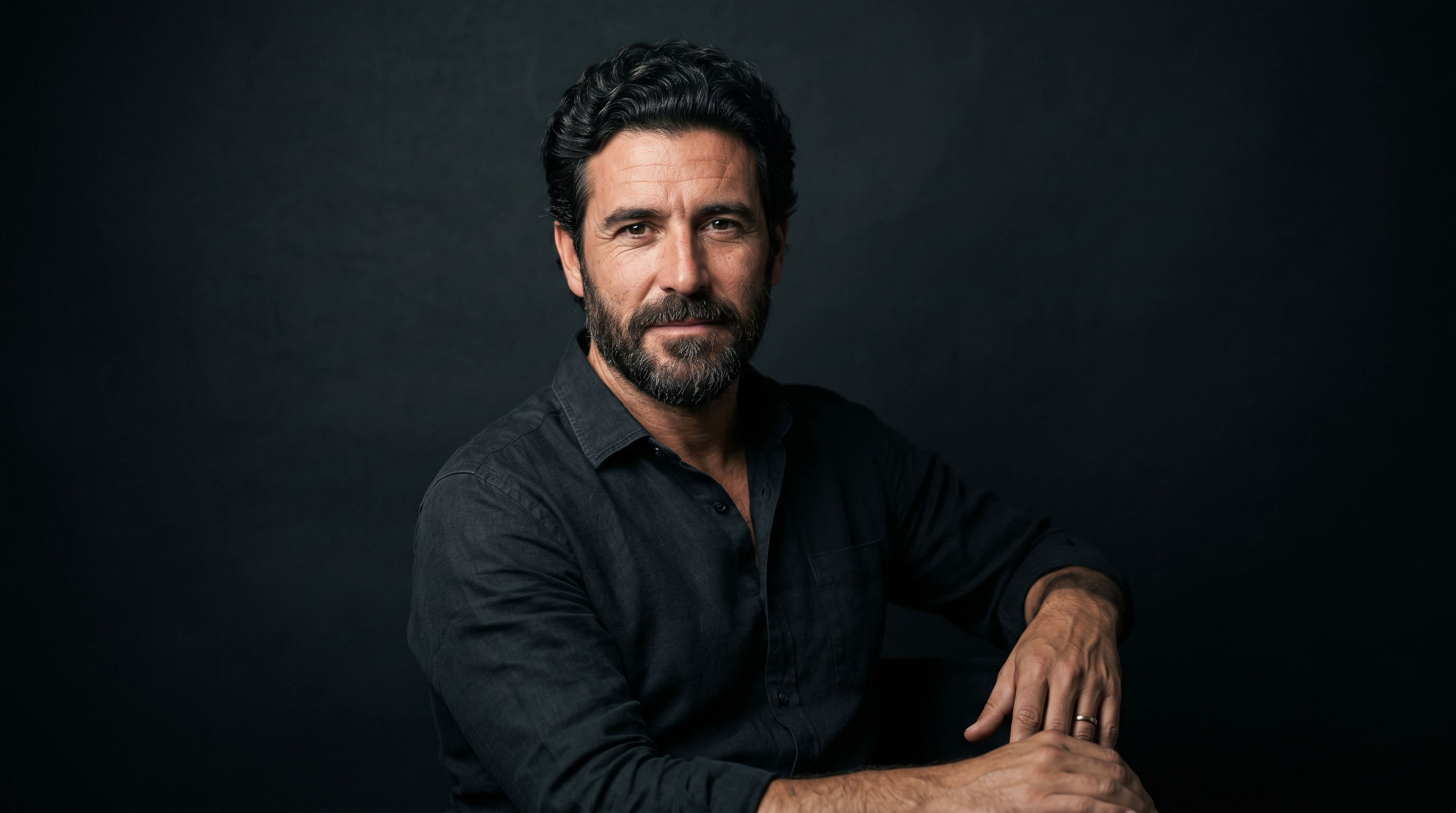 Hombre mediterráneo con cabello sano y cuidado, retrato premium sobre fondo oscuro