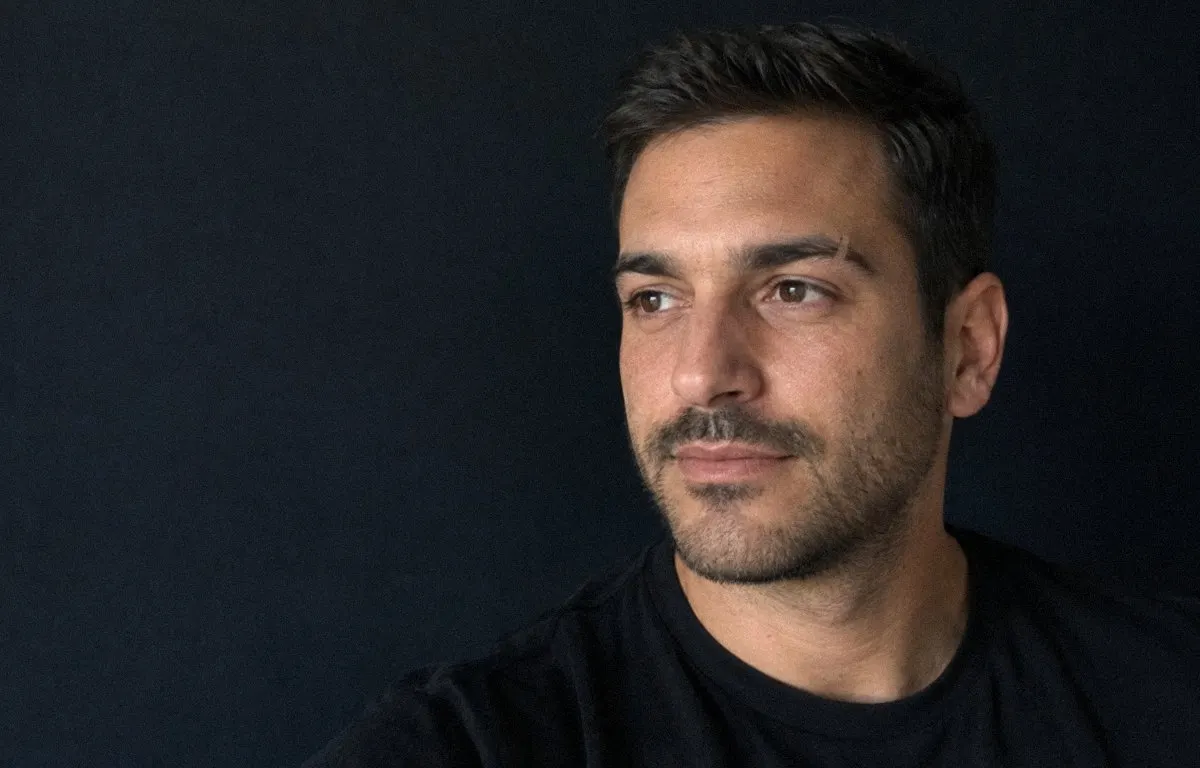 Retrato de un hombre mediterráneo con cejas densas y ordenadas, sobre fondo antracita